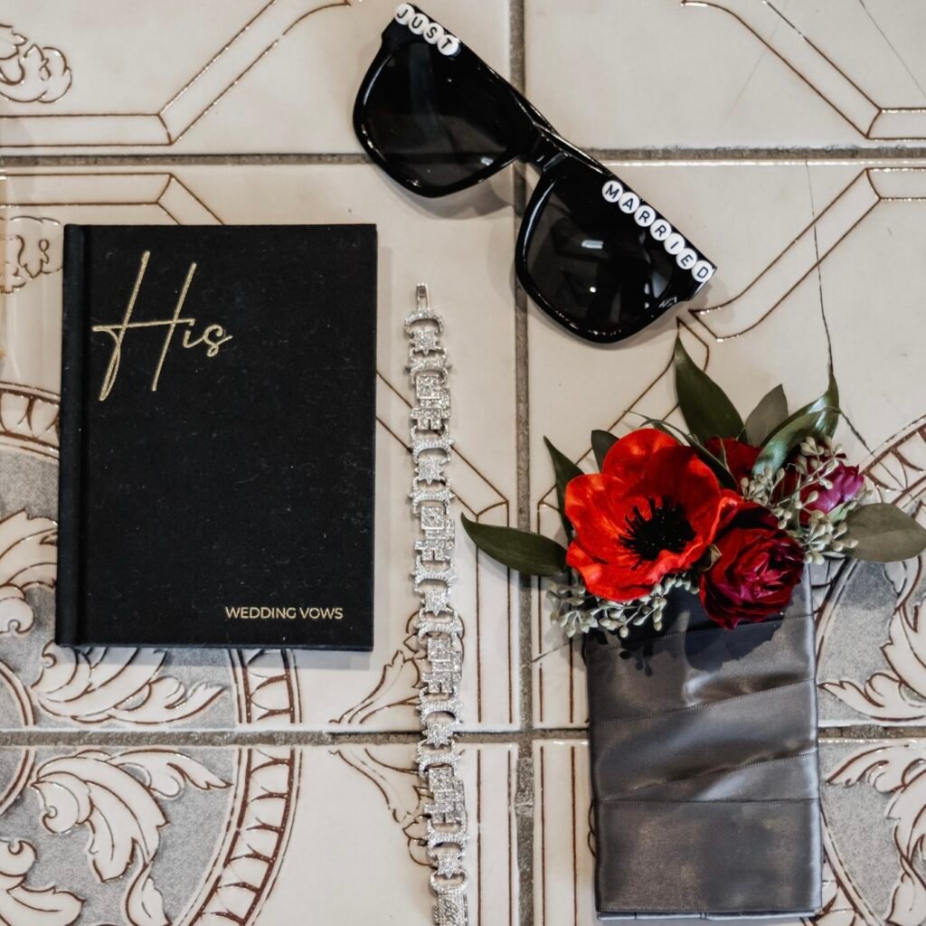 Flat lay of a vows book with a red poppy boutonniere