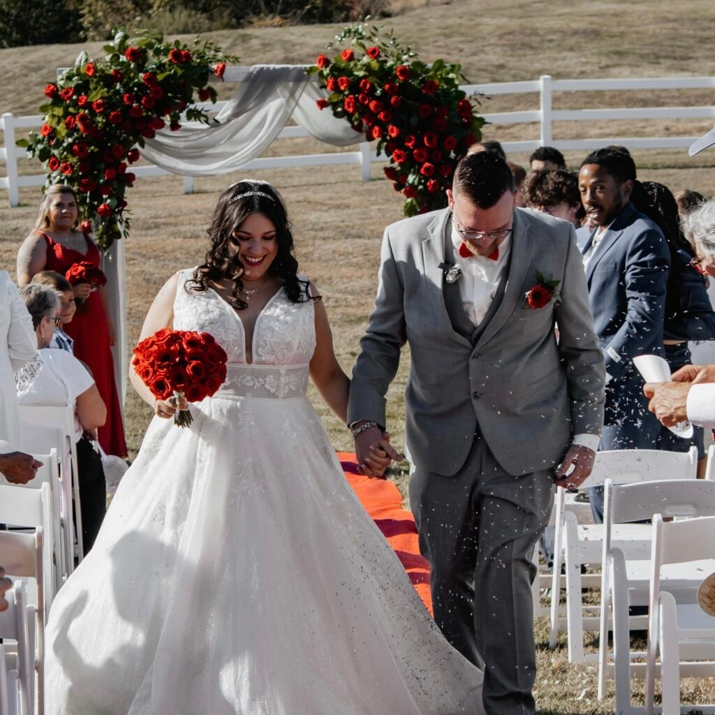Couple's first dance framed by a red rose ceremony arch
